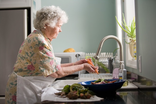 Older woman washing dishes in a sink