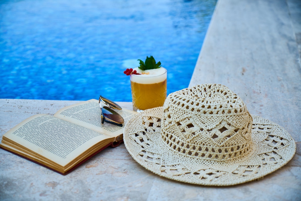 A book and a cocktail next to the pool.