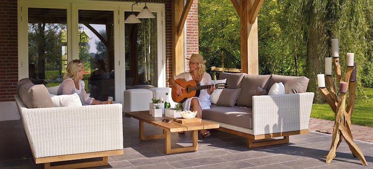 two women sitting at a deck, one of them playing the guitar