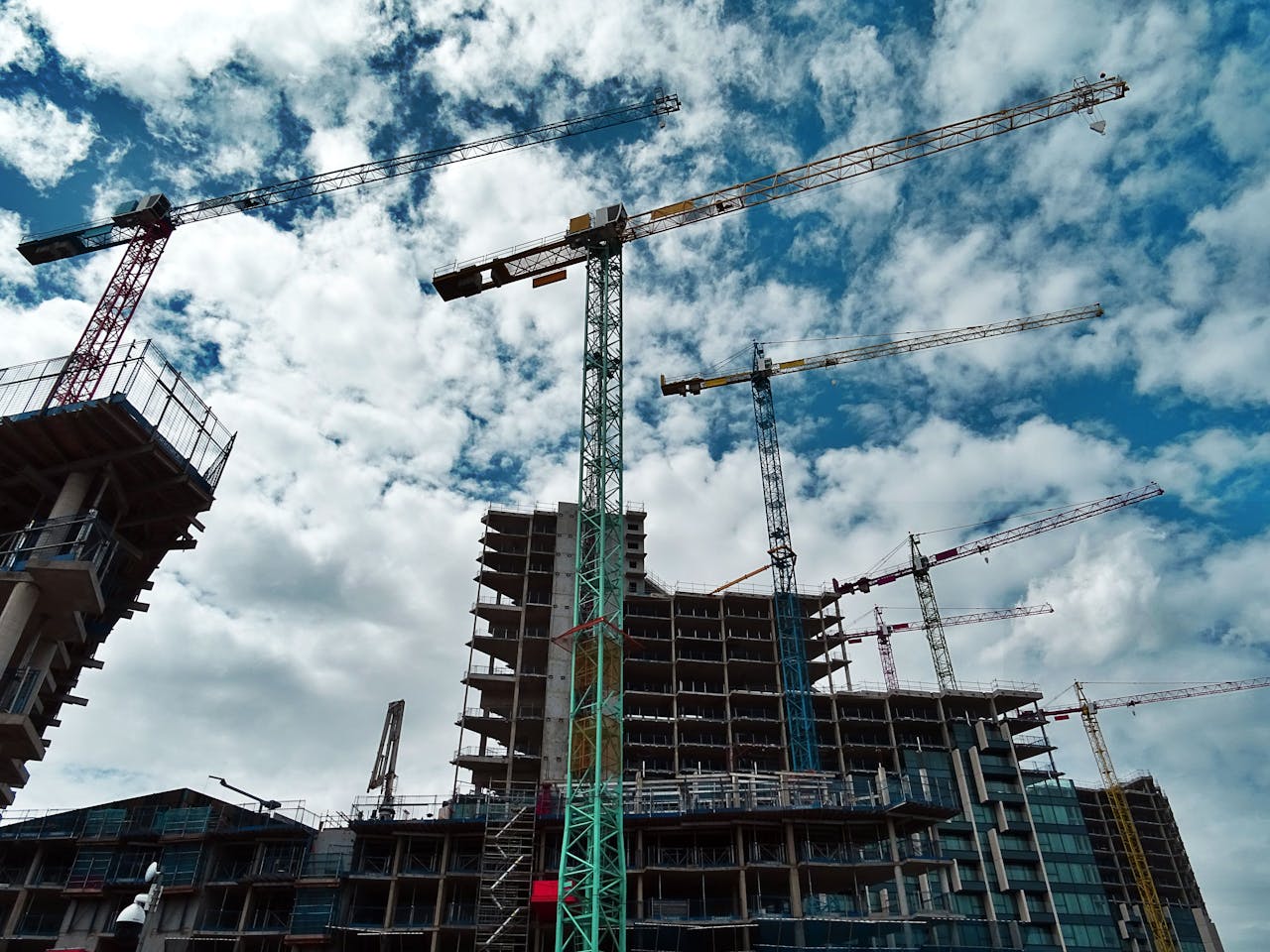 A construction site with cranes and a clouded sky