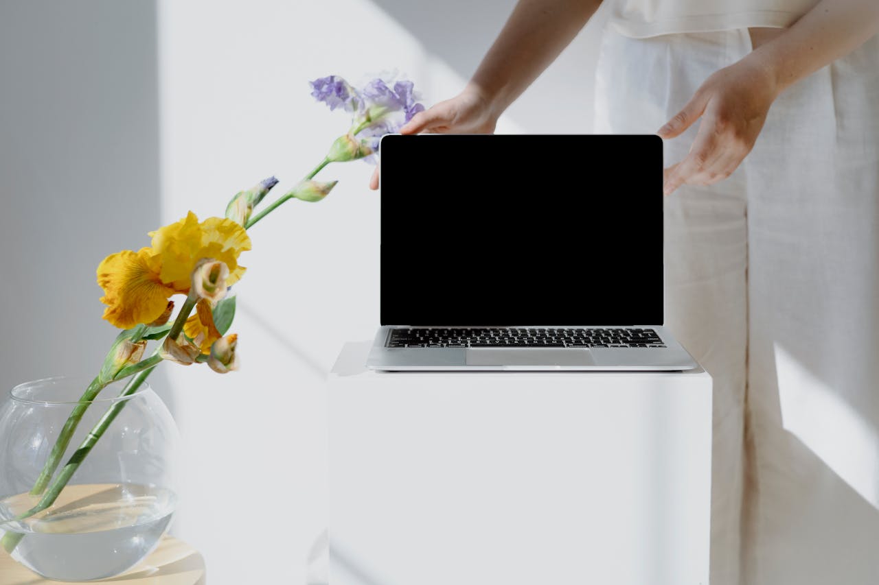 A person holding a laptop beside a flower